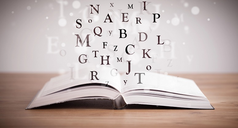 Foto decorativa de un libro abierto con letras flotando en el aire