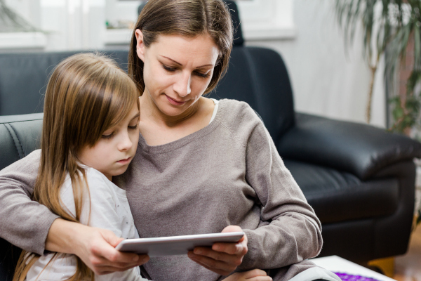 Madre apoyando a su hija mientras revisan juntas la tablet